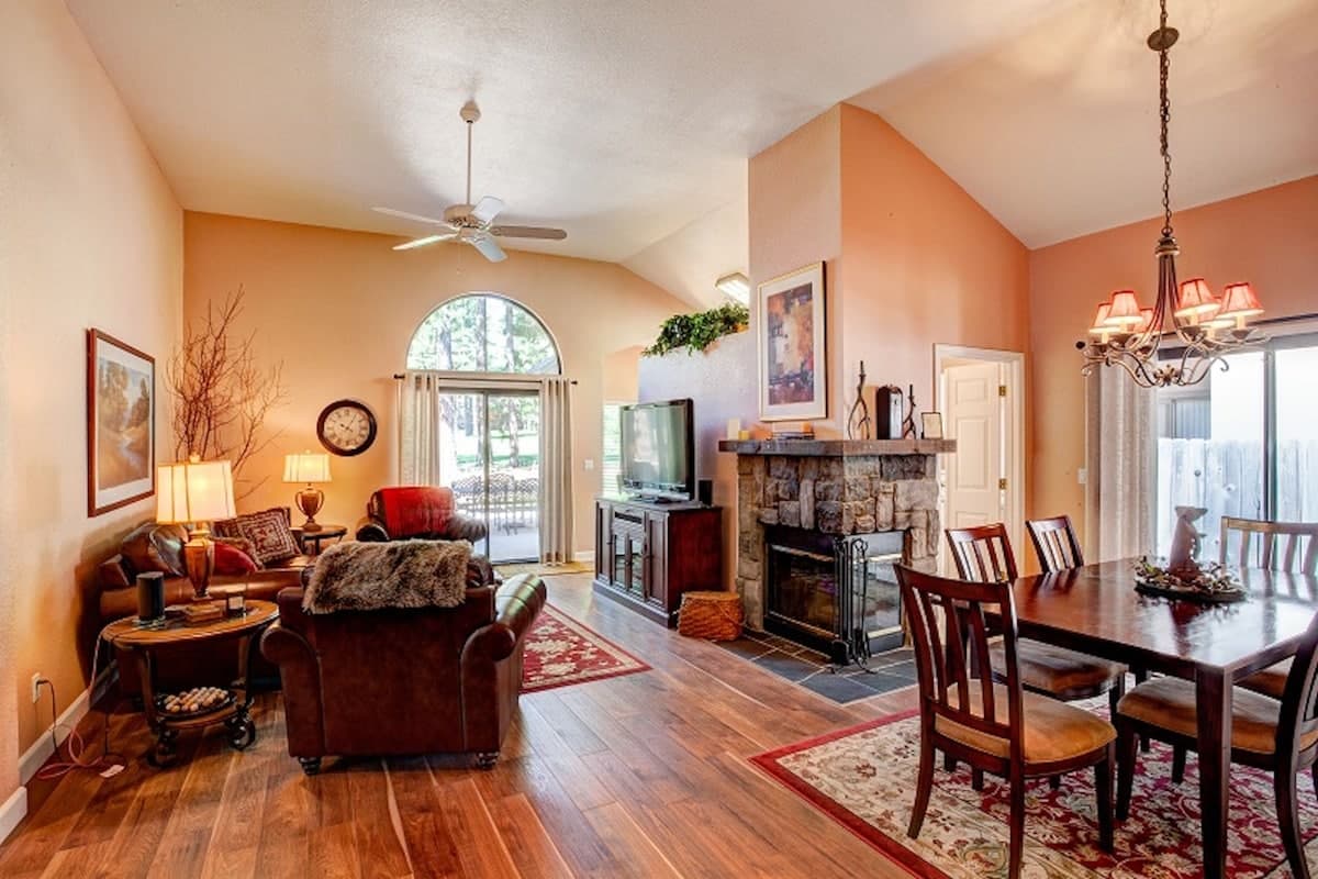 Living and dining with a stone fireplace, arched window and a slider onto the deck at 129 Cottonwood, Plumas Pines — 3-bedroom Plumas Pines vacation rental in Graeagle, CA