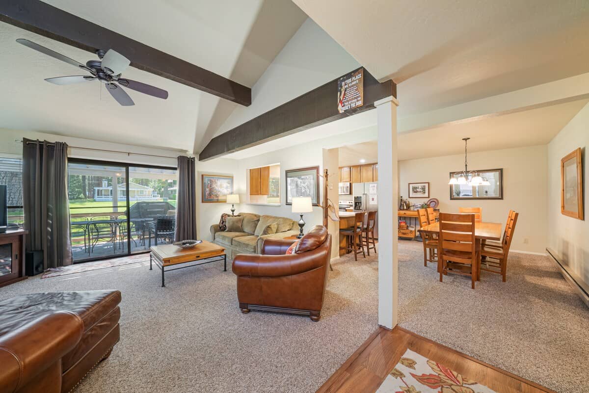 Living room with a vaulted beamed ceiling and a slider onto the deck, patio set and greenbelt beyond at 35 Aspen, Plumas Pines — 4-bedroom Plumas Pines vacation rental in Graeagle, CA